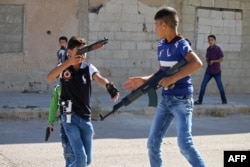 Syrian children play with fake plastic guns in the streets of Daraa, southern Syria, on June 15, 2018.