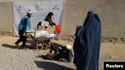 A UNHCR worker pushes a wheelbarrow loaded with aid supplies for a displaced Afghan family outside the distribution center on the outskirts of Kabul, Afghanistan, Oct. 28, 2021. 