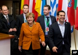 Greek Prime Minister Alexis Tsipras, right, walks with German Chancellor Angela Merkel, center, as they leave an EU summit in Brussels, March 8, 2016.