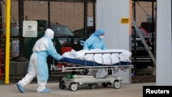 Healthcare workers wheel the body of deceased person from the Wyckoff Heights Medical Center to a temporary morgue area during the outbreak of the coronavirus disease (COVID-19) in the Brooklyn borough of New York City, New York, U.S., April 2, 2020. REUT