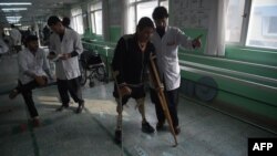 FILE - An Afghan doctor, right, assists a survivor of a land mine blast at a hospital run by the International Committee of the Red Cross for war victims and the disabled in Kabul, Feb. 13, 2018. The Taliban announced Oct. 11, 2018, that it would allow the ICRC to fully resume operations in Afghanistan.