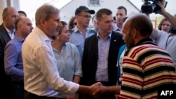 Commissioner for European Neighborhood Policy Johannes Hahn shakes hands with a migrant at a camp near Gevgelija on Sept. 19, 2015.