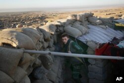 FILE - A Kurdish peshmerga fighter pauses during an operation to retake the northern Iraqi town of Sinjar, Nov. 12, 2015.