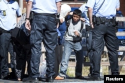 FILE - A crying migrant child tries to prevent his mother from leaving a train to get into a bus at Rodby train station, south of Denmark, Sept. 9, 2015.