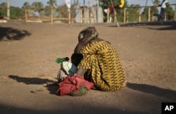 FILE- A South Sudanese refugee woman sits with her child at a refugee collection center in Palorinya, Uganda, Feb. 16, 2017.