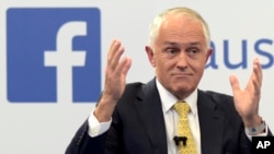 FILE - Australian Prime Minister Malcolm Turnbull raises his hands as he speaks during a leaders debate hosted by Facebook Australia and News.com.au in Sydney, June 17, 2016. The Australian government on July 14, 2017, proposed a new cybersecurity law to force global technology companies such as Facebook and Google to help police by unscrambling encrypted messages sent by suspected extremists and other criminals. 