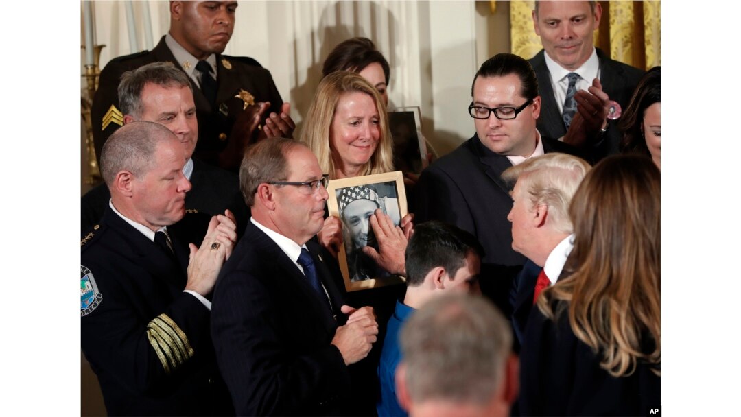 Jeanne Moser, center, of East Kingston, N.H., watches as President Donald Trump reaches out to touch a photo of her son Adam Moser, during a event to declare the opioid crisis a national public health emergency. Adam was 27 when he died from an apparent fentanyl overdose.