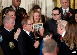 Jeanne Moser, center, of East Kingston, N.H., watches as President Donald Trump reaches out to touch a photo of her son Adam Moser, during a event to declare the opioid crisis a national public health emergency. Adam was 27 when he died from an apparent fentanyl overdose.