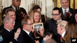 Jeanne Moser (tengah), dari East Kingston, N.H., memperhatikan ketikan President Donald Trump menyentuh foto anak laki-lakinya Adam Moser, pada saat acara pernyataan krisis opioid sebagai keadaan darurat kesehatan masyarakat, Kamis, 26 Oktober 2017.