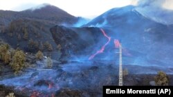 Scientists with the Canary Islands' volcanology institute, Involcan, study the melted rock being erupted from a volcano on the Canary island of La Palma, Spain, on October 30, 2021. (AP Photo/Emilio Morenatti)