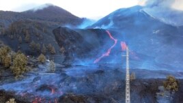 Scientists with the Canary Islands' volcanology institute, Involcan, study the melted rock being erupted from a volcano on the Canary island of La Palma, Spain, on October 30, 2021. (AP Photo/Emilio Morenatti)