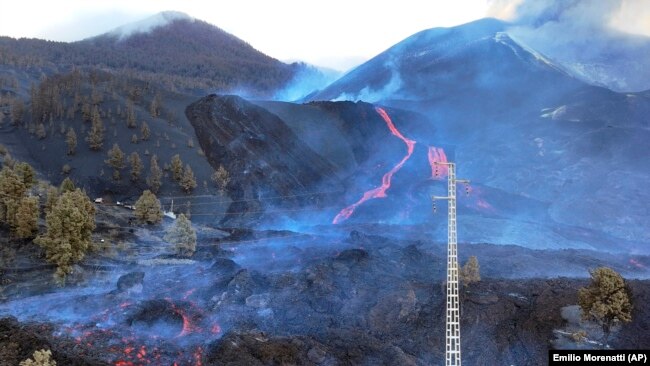 Scientists with the Canary Islands' volcanology institute, Involcan, study the melted rock being erupted from a volcano on the Canary island of La Palma, Spain, on October 30, 2021. (AP Photo/Emilio Morenatti)