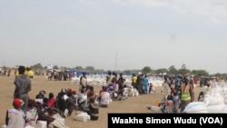 Displaced South Sudanese wait on Saturday, March 21, 2015, in Ganyiel, Unity state for sacks of food provided by the World Food Program (WFP) to be distributed. 