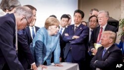 FILE - In this photo made available by the German Federal Government, German Chancellor Angela Merkel, center, speaks with U.S. President Donald Trump, seated at right, during the G7 Leaders Summit in La Malbaie, Quebec, Canada, on June 9, 2018.