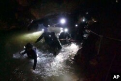 In this handout photo released by Tham Luang Rescue Operation Center, Thai rescue teams walk inside cave complex where 12 boys and their soccer coach went missing, in Mae Sai, Chiang Rai province, in northern Thailand, Monday, July 2, 2018.