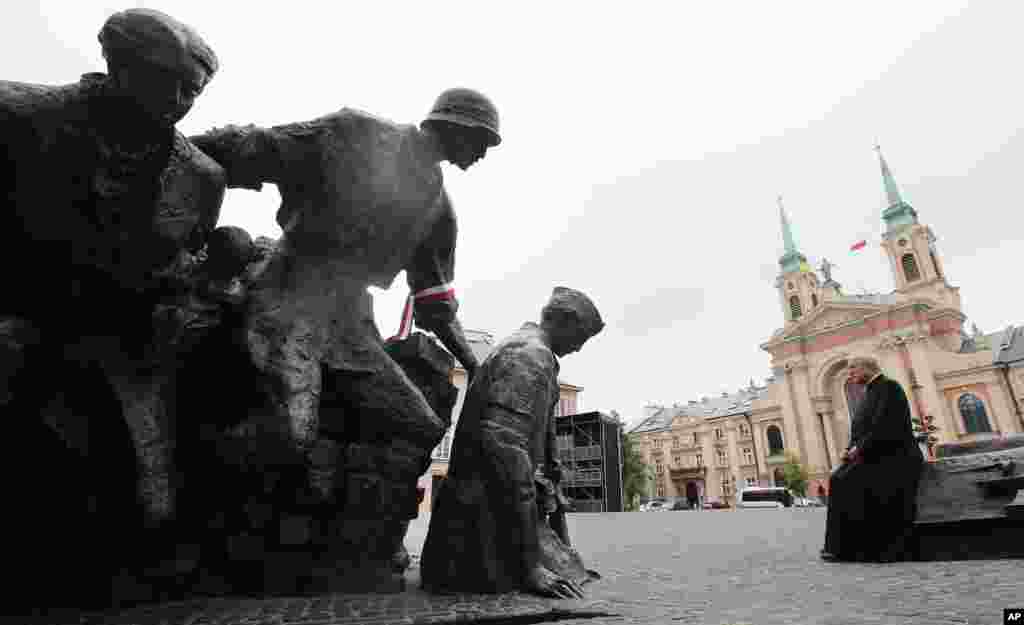 Một linh mục Ba Lan ngồi trước của tượng đài kỷ niệm cuộc Nổi dậy Warsaw tại Warsaw. Vào ngày kỷ niệm 70 năm cuộc nổi dậy, Ba Lan tưởng nhớ những chiến sĩ và nạn nhân của cuộc nổi loạn chống lại Đức Quốc xã bằng cách đặt vòng hoa, bật còi báo động và hát những giai điệu của phong trào nổi dậy.