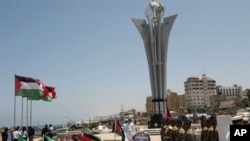 Hamas security men stand near flags from different countries and a monument built to commemorate the first anniversary of the death of nine Turks, who were shot dead last May when Israeli naval commandos seized a Turkish ship that was part of a flotilla t
