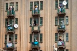 Residents watch from their balconies South African police and National Defense Forces search a local bar they thought was illegally open in downtown Johannesburg on Monday March 30, 2020.