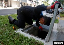 A member of a pest control team inspects drains at a Zika cluster in Singapore, Sept. 2, 2016.