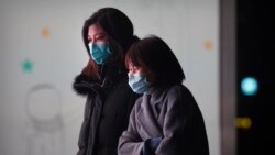 People wearing face masks to protect against the spread of the coronavirus walk outside of an office complex in Beijing, Wednesday, Jan. 13, 2021.