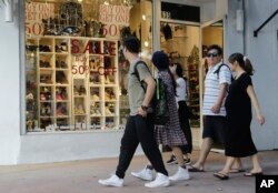 FILE - People walk past a shoe store at Lincoln Road Mall in Miami Beach, Fla., Feb. 3, 2016. A University of Michigan survey's measure of current economic conditions, released Jan. 18, 2019, decreased to 110.0 from a reading of 116.1 in December 2018. Its measure of consumer expectations fell to 78.3, the lowest since October 2016, from 87.0 in late December.