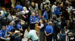 Agentes de Seguridad en el Transporte (TSA) revisan pasajeros en el aeropuerto internacional de Tacoma, en Washington.