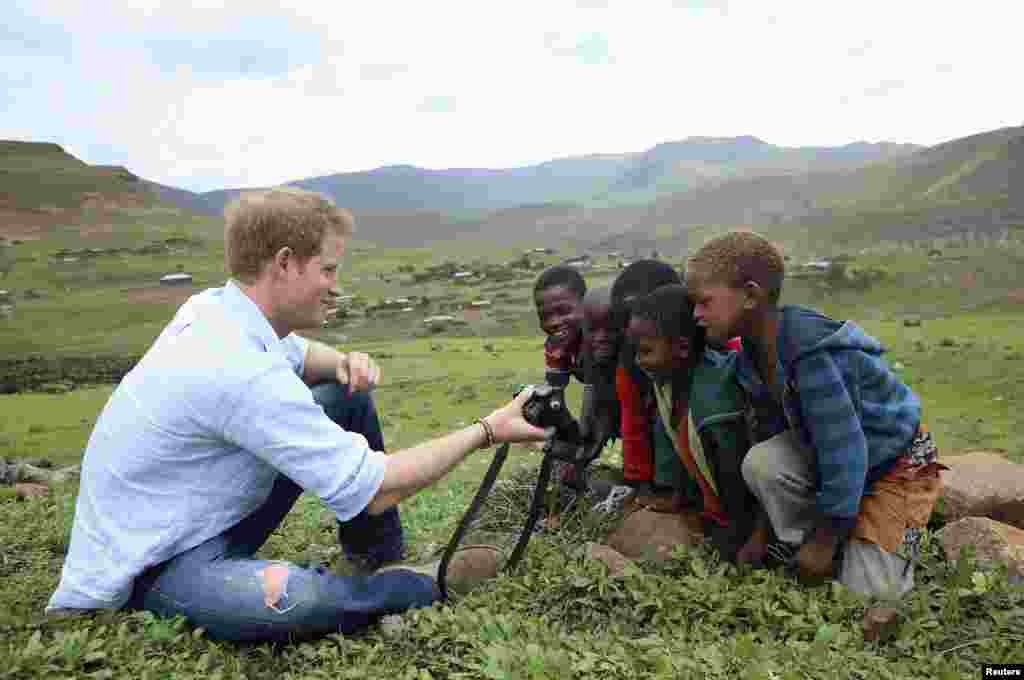 Pangeran Harry dari Inggris menunjukkan hasil foto jepretannya kepada anak-anak di Sentebale, Mokhotlong, Lesotho.