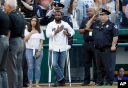 Injured Capitol Hill Police officer David Bailey, center, holds his hand over his heart during Congressional baseball game.