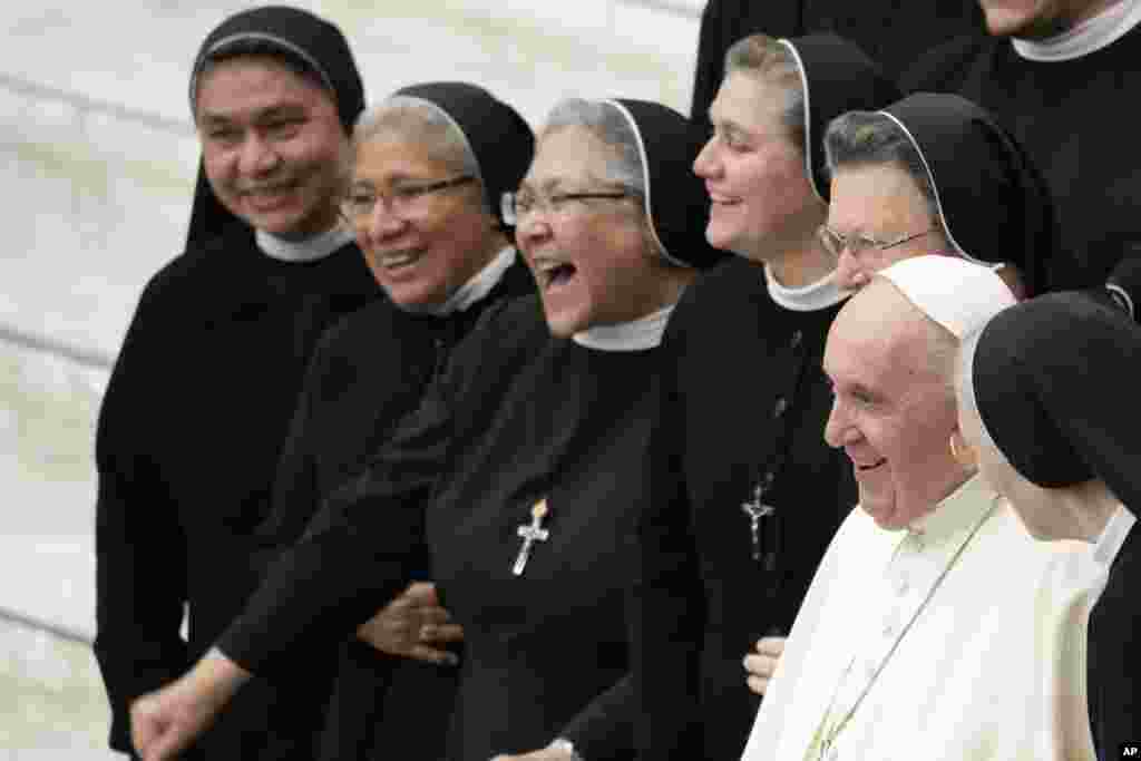 Pope Francis stands for a picture with a group of nuns at the end of his weekly general audience in the Paul VI Hall the Vatican.