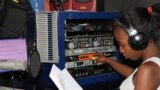 Florence Mwale, host of Business Today show at Capita Radio, must press many buttons in an audio production studio. (L. Masina for VOA)