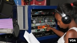 Florence Mwale, host of Business Today show at Capita Radio, must press many buttons in an audio production studio. (L. Masina for VOA)