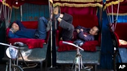 Chinese trishaw drivers take nap while waiting for customers at a hutong alley near the drum tower, a tourist spot in Beijing, China.