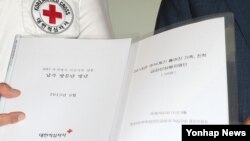 남북한이 이산가족 상봉 대상자 최종 명단을 교환한 지난 16일, 김성근 한국측 남북교류팀장(오른쪽)과 직원이 서울 대한적십자사에서 명단이 담긴 파일을 들어보이고 있다. 