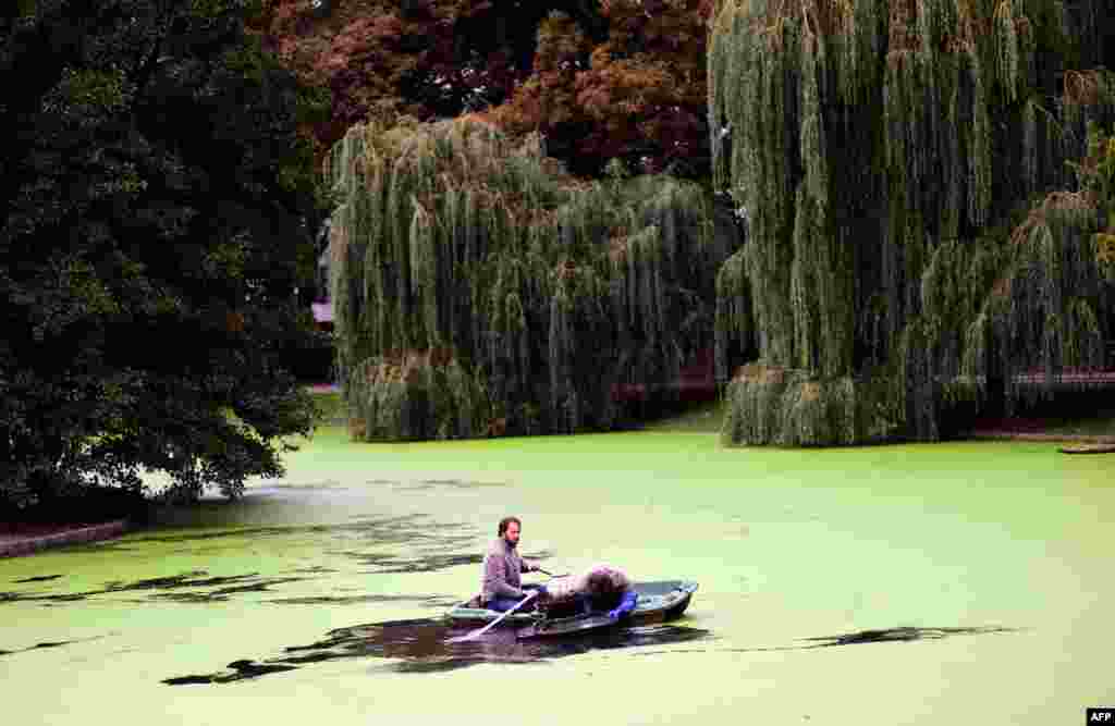 Two workers clear a water circulation system on a lake in a park in Brussels, Belgium. 