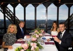 President Donald Trump, first lady Melania Trump, French President Emmanuel Macron his wife, Brigitte Macron, sit for dinner at the Jules Verne Restaurant on the Eiffel Tower in Paris, July 13, 2017.