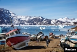 FILE - A man walks to his boat past a number of abandoned and dry-docked boats in the town of Tasiilaq, Greenland, June 15, 2018.