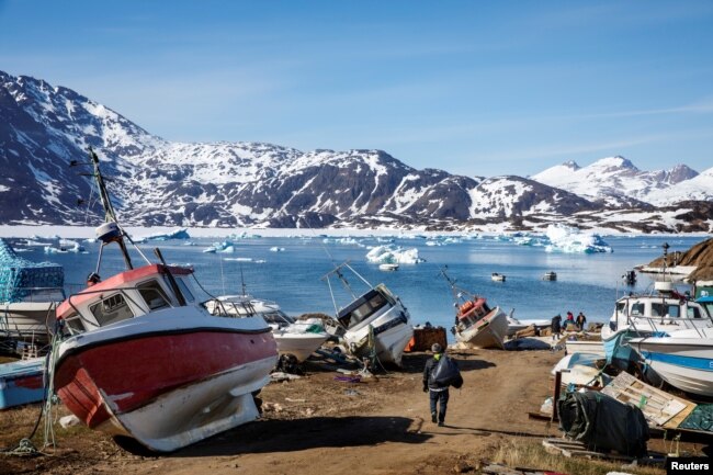 FILE - A man walks to his boat past a number of abandoned and dry-docked boats in the town of Tasiilaq, Greenland, June 15, 2018.