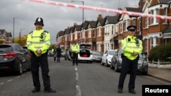FILE - Police stand next to terraced housing in Harlesden Road, north London, April 28, 2017. British counterterrorism police said they had thwarted an active plot in an armed raid, the second major security operation in the British capital in the space of a few hours.
