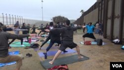 Yoga enthusiasts participate in a simultaneous session on both sides of the U.S.-Mexico border wall at Peace Park near San Diego, Calif., Feb. 11, 2017. (A. Martinez/VOA)