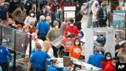 Travelers line up at the south security checkpoint as traffic increases with the approach of the Thanksgiving Day holiday Nov. 23, 2021, at Denver International Airport in Denver.