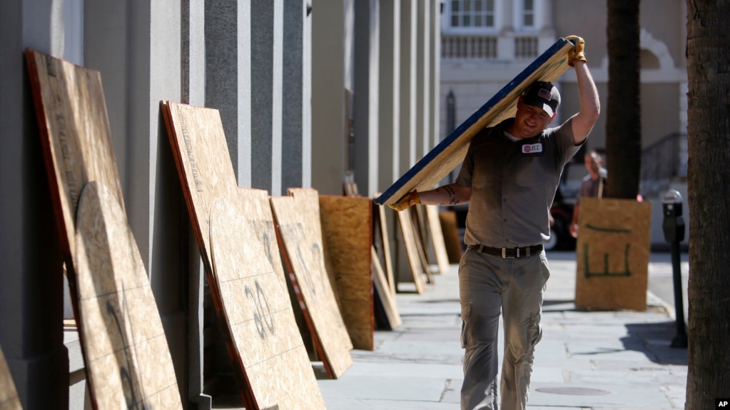 Preston Guiher carga un panel de madera prensada mientras se prepara cubrir un banco de Wells Fargo en anticipaciÃ³n a la llegada del huracÃ¡n Florence, en Charleston, Carolina del Sur, el martes 11 de septiembre de 2018. (AP/Mic Smith)