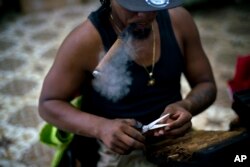 A roller puffs on a cigar while working at La Corona cigar factory in Havana, Cuba, March 2, 2017.