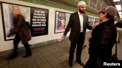 FILE - Cyrus McGoldrick, a member of the Council on American-Islamic Relations, talks to a woman in the Times Square subway station in New York.
