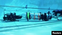 A device by Elon Musk's SpaceX and The Boring Company, designed to help rescue the remaining members of a soccer team trapped in a flooded cave in Chiang Rai, Thailand, is being tested in a swimming pool in Los Angeles, California, in this still image taken from an undated video obtained from social media.