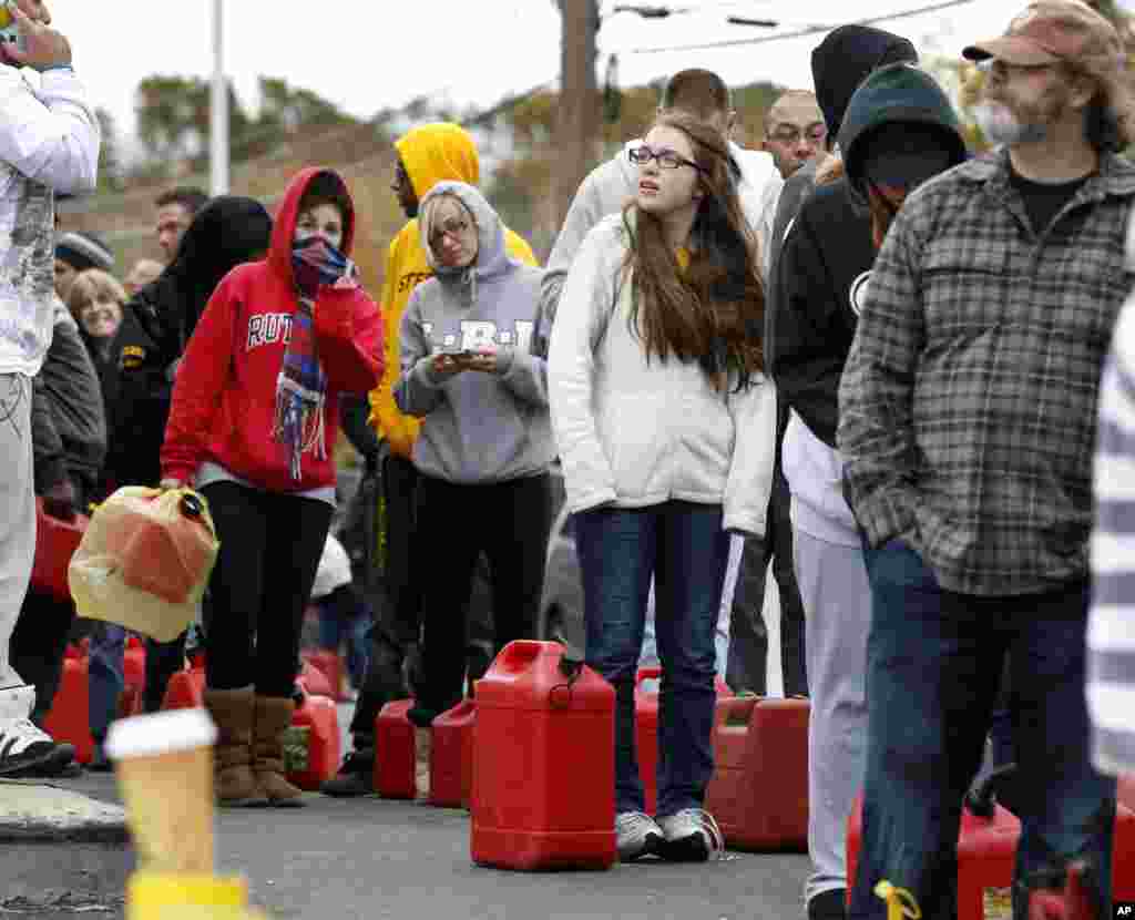 As temperatures begin to drop, people wait in line to fill containers with gas at a Shell gasoline filling station Nov. 1, 2012, in Keyport, N.J.