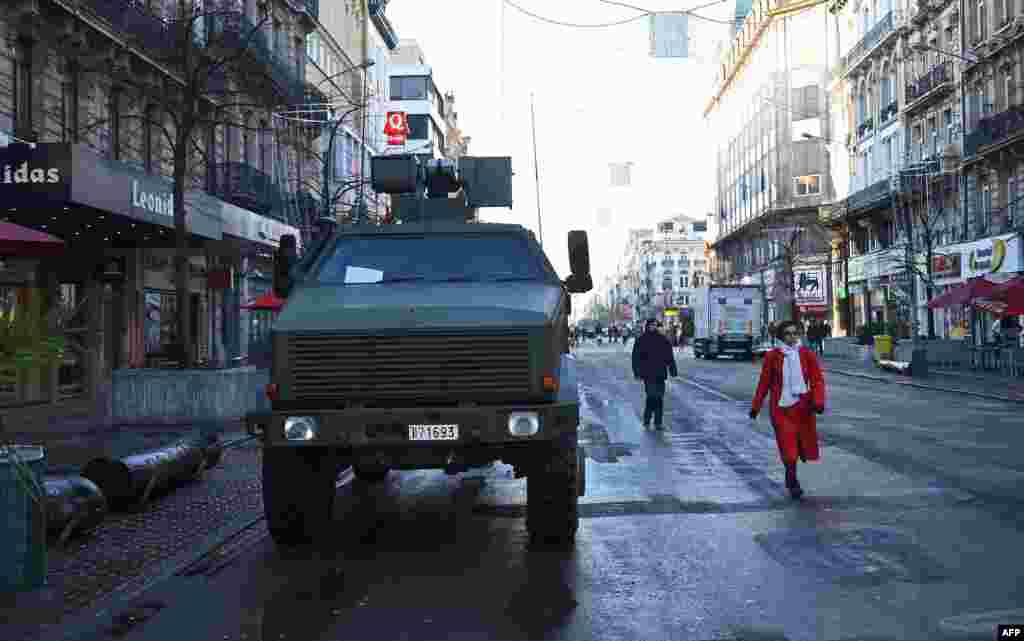 People walk past an armoured personnel carrier in Brussels as the Belgian capital remains on the highest possible alert level.