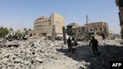 FILE - Fighters from the Syrian Democratic Forces (SDF), a U.S.-backed Kurdish-Arab alliance, walk through the rubble in an eastern area of the embattled city of Raqqa in northern Syria, Aug. 15, 2017.