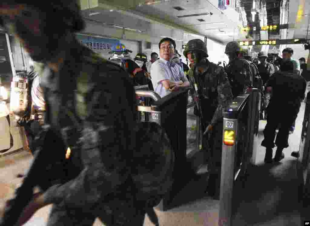 South Korean army soldiers pass by ticket gates during a South Korea-U.S. joint military exercise at a subway station in Seoul, August 19, 2013.