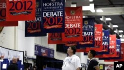 Billy Koske, left, and Jose Reyes look at signs hanging in the media filing center before Tuesday's presidential debate between President Barack Obama and Republican presidential candidate, former Massachusetts Gov. Mitt Romney, October 15, 2012.