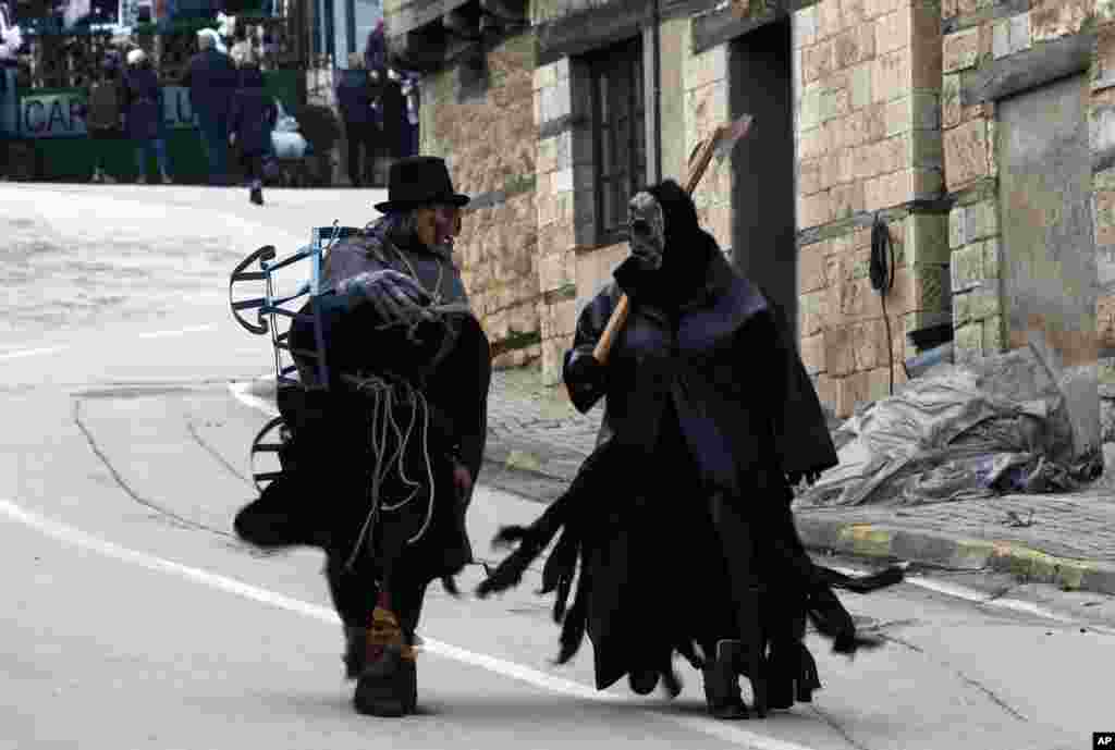 People wearing costumes walk through a street ahead of the carnival parade in the village of Vevcani, in the southwestern part of North Macedonia.